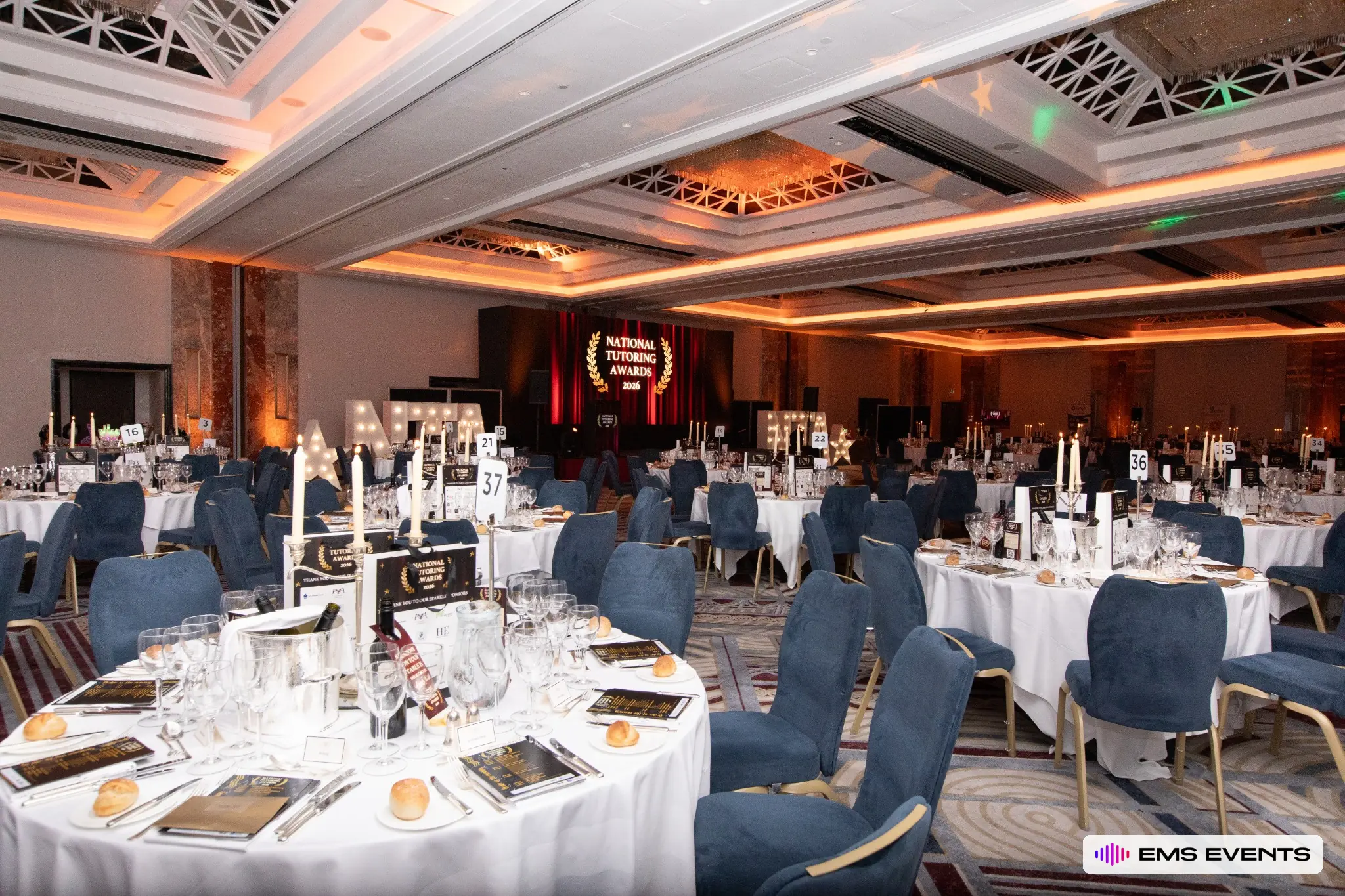Banquet tables set with candles and awards programmes before The Tutors' Association's 5th National Tutoring Awards ceremony