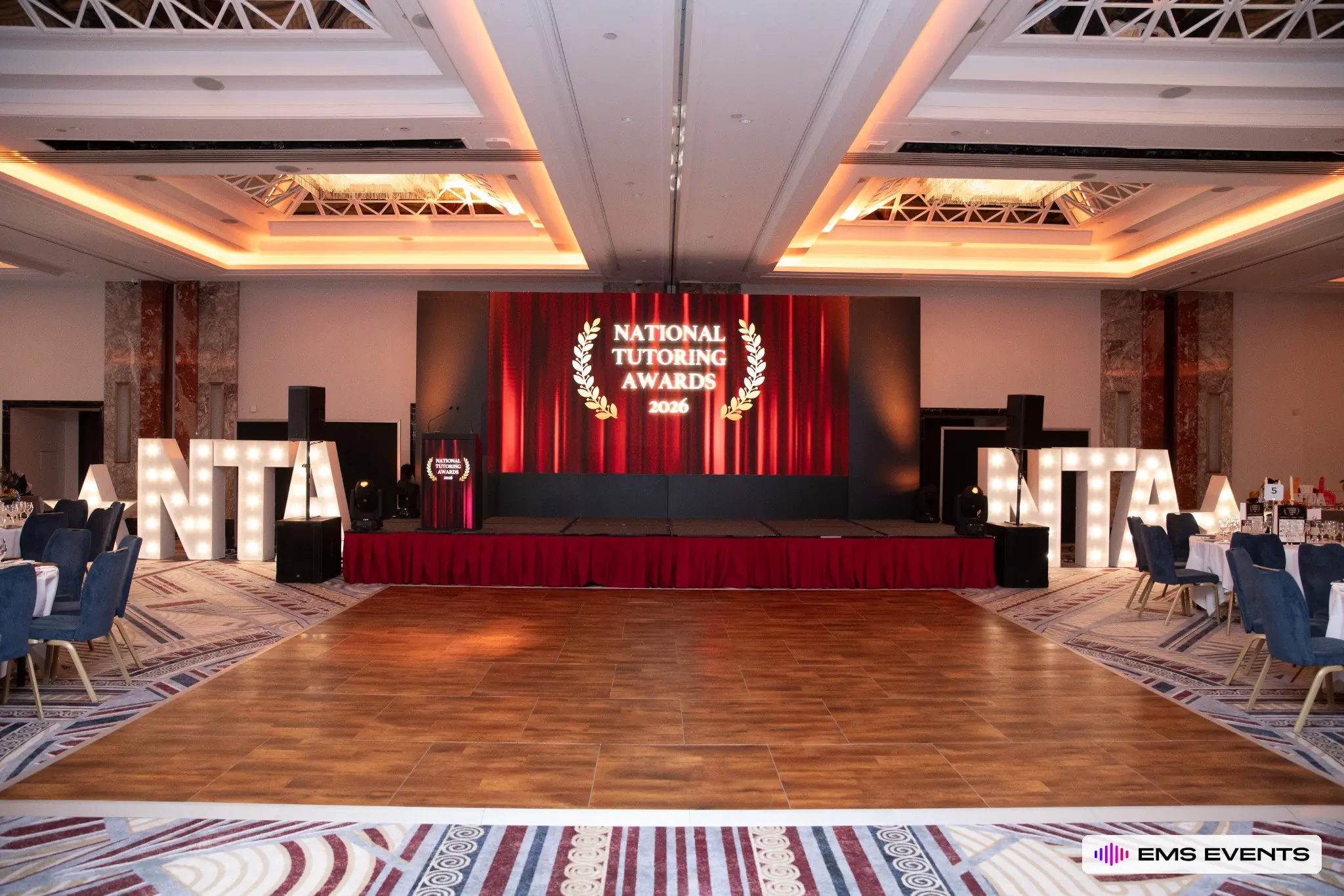 Red curtain LED backdrop and illuminated NTA marquee letters for The Tutors' Association's 5th National Tutoring Awards stage production